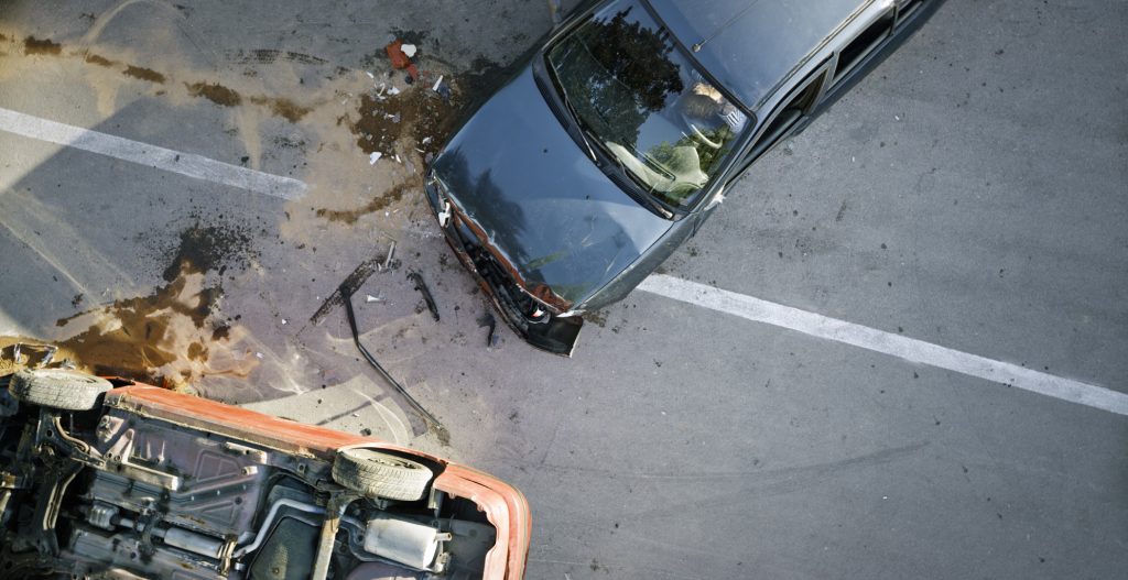car accident involving a crushed fender and a rolled car.